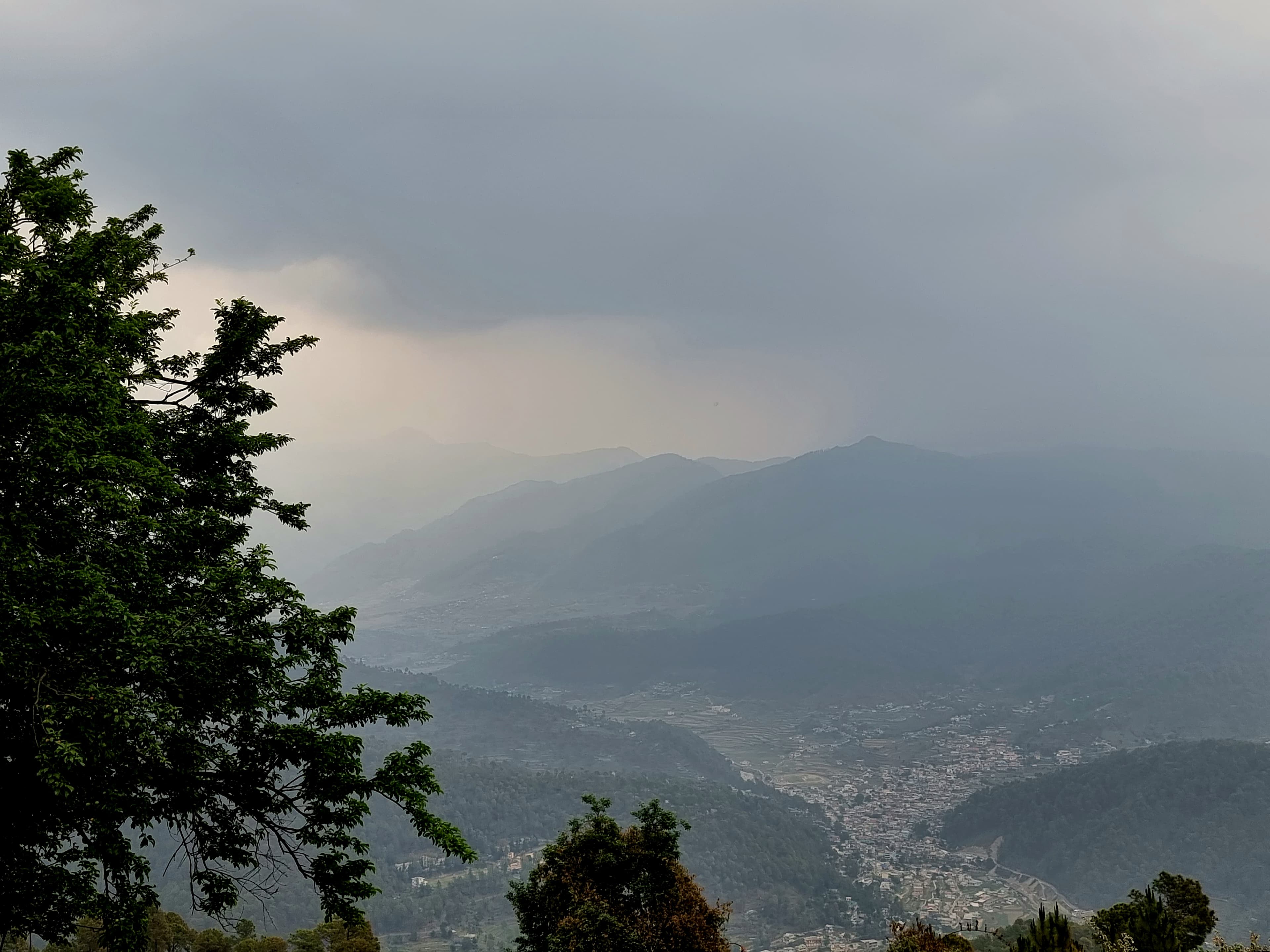 Mist drifting up from the Yamuna valley above Purola, layered ridges in late May.